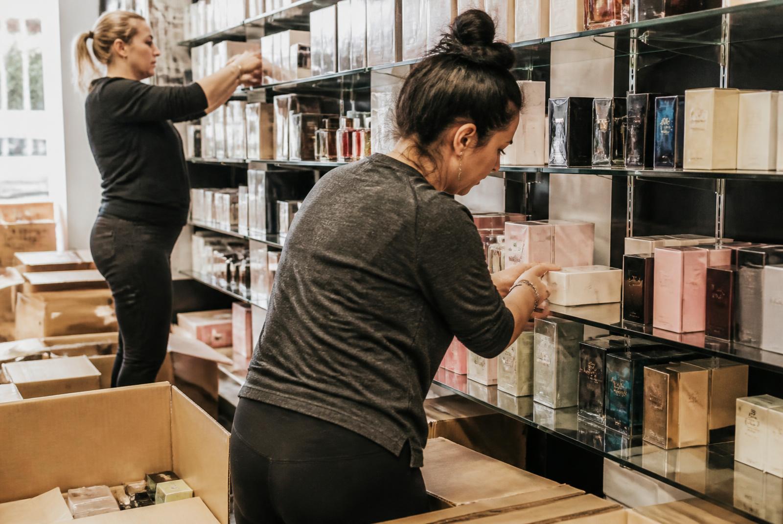 Dos personas del equipo reponiendo producto en las estanterías de una perfumería